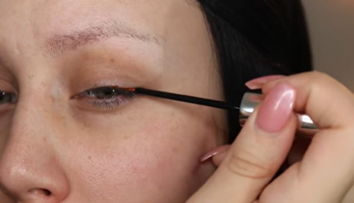 Boostlash Reviews: Woman showing the correct use of boostlash serum on her upper eyelids
